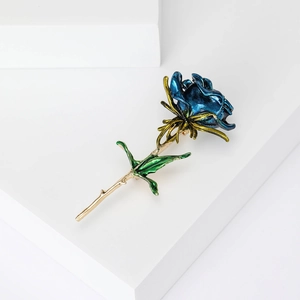 Macro detail of a blue enamel rose brooch with green leaves on gold plated metal