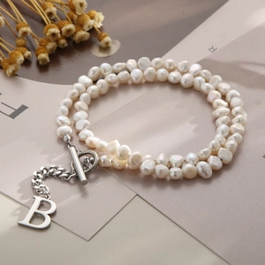 Detail view of baroque pearls with a silver B-letter pendant and toggle clasp