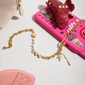 Detailed shot of 18K gold-plated star cross and pearl charms on a dainty chain