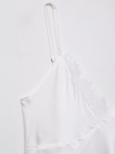 Détail du tissu en satin blanc avec bordure en dentelle délicate et fines bretelles