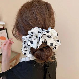 Detailed back view of a floral silk-like scrunchie used in a low ponytail hairstyle