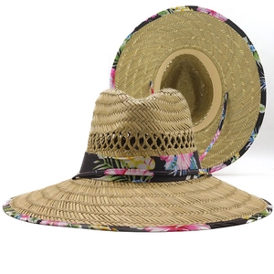 Dettaglio cappello in paglia con bordo floreale e cordino regolabile per esterni