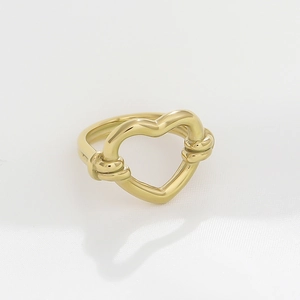 Close-up of golden hollow heart ring with braided knot details on a white background