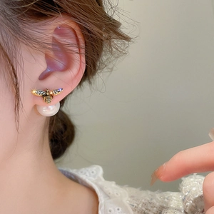 Detail shot of elegant bee earrings with sparkling crystals and white pearl drop on model