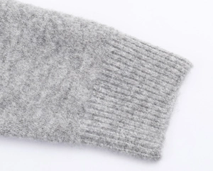 Detailed macro view of the grey knitted sweater showing soft fabric texture and ribbed cuffs