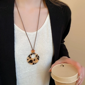 Detail of retro resin round pendant with leopard print and orange bead on brown wax cord