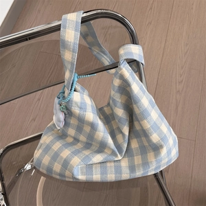Close-up of blue and beige checkered canvas tote bag with a cute plush doll charm