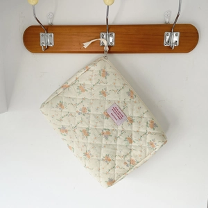 Close-up of beige quilted floral makeup bag with orange flowers hanging on a hook