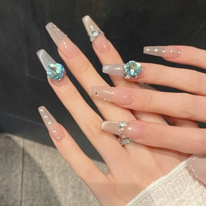 Detailed macro view of long coffin press-on nails with blue K9 crystals and cat-eye effect