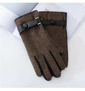 Detail of brown herringbone wool and black leather gloves with wrist strap and metal buckle
