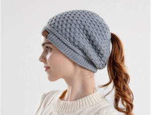 Detailed side view of grey knit ponytail beanie with ear protection and leather label