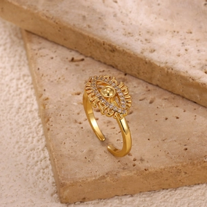 Macro shot of gold adjustable Evil Eye ring with zircon stones on beige stone display