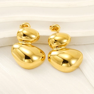 Macro view of polished gold teardrop earrings with fluid liquid metal texture on silk background