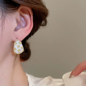 Detail of French vintage C-shaped drop oil floral earring on female model's ear
