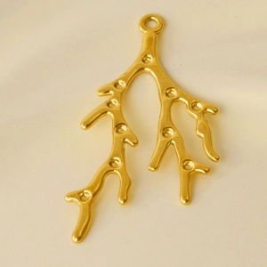 Macro shot of gold-plated coral branch pendant with multiple circular inlay slots
