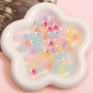 Frosted colorful acrylic square beads with core dots on a floral ceramic plate