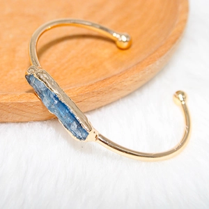 Close-up of a raw blue crystal stone set in a gold-plated adjustable cuff bracelet