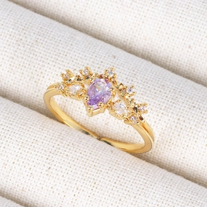 Macro shot of a vintage 18K gold crown ring with pear-cut purple zircon and white diamonds