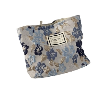 Blue and beige floral jacquard makeup bag with metal zipper on a white background
