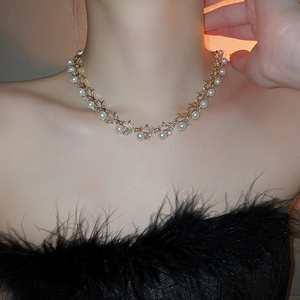 Close-up of golden vine necklace with white pearls and sparkling crystals on model
