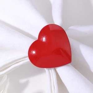 Gros plan d'un rond de serviette en forme de cœur rouge brillant sur une serviette blanche