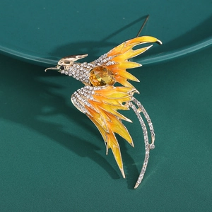 Detailed view of phoenix brooch with yellow enamel and sparkling crystal inlay