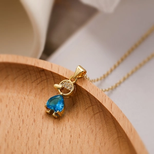 Macro shot of 18K gold heart-shaped blue zircon pendant necklace with small crystal details