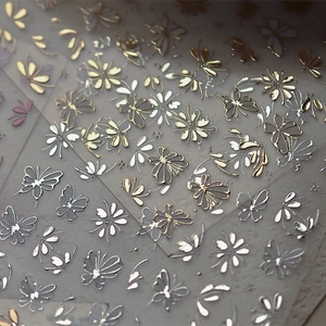 Detailed macro view of gold and silver metallic butterfly and floral nail art stickers