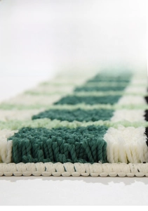 Gros plan d'un tapis de bain épais avec tissage à carreaux vert et blanc texturé