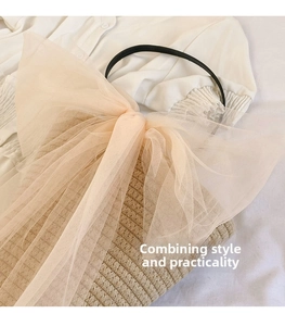 Detailed view of woven handbag with large pink tulle bow and black ring handle