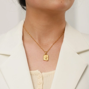 Detail of 18K gold stainless steel necklace with square angel relief pendant on a model