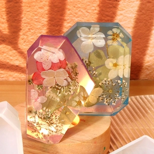 Macro view of crystal faceted resin ornaments with dried flowers on a lighted wooden base