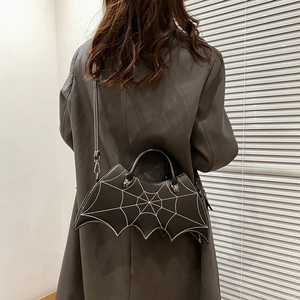 Detail of black bat PU leather bag with white spiderweb stitching and bat metal hardware