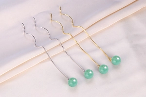 Detailed close-up of S925 silver and gold wave ear threads with green aventurine beads