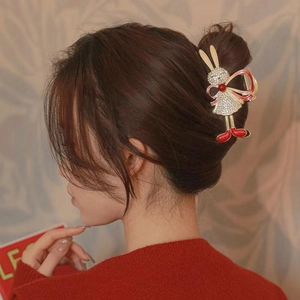 Golden metal bunny hair claw with red bow and rhinestones shown on model hair
