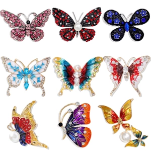 Set of nine colorful butterfly brooches with rhinestones and pearls on white background