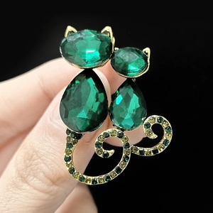 Detail of cute twin cat brooch with green faceted stones and golden metal base
