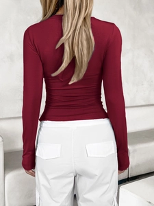 Vista posteriore di una maglia aderente a maniche lunghe rosso scuro e pantaloni bianchi