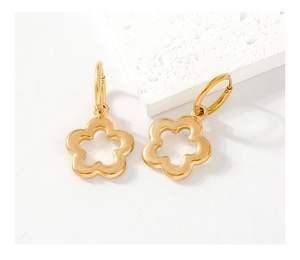 Detailed close-up of gold-plated flower earrings on a textured stone display