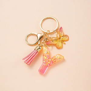Detail of pink resin letter Y keychain with gold sequins, butterfly charm and tassel