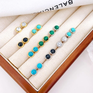 Minimalist gold and silver stud earrings featuring turquoise and onyx stones on a jewelry tray