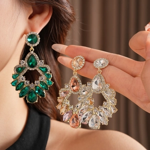 Gros plan de boucles d'oreilles géométriques en goutte avec cristaux émeraude et champagne