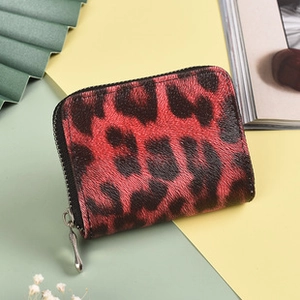 Detailed view of red and black leopard print wallet with silver zipper on color block background