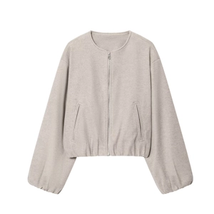 Detail of soft beige bomber jacket featuring a metal zipper and ribbed cuffs