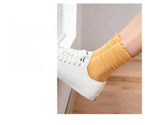 Close-up of bright yellow ribbed cotton socks with elegant ruffled edges and sneakers