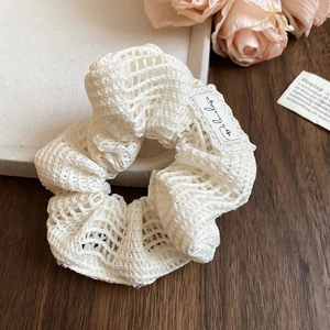Gros plan sur un chouchou en tricot blanc avec une texture de maille ajourée raffinée