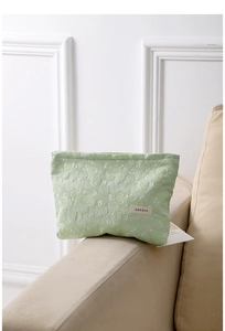 Close-up of light green floral jacquard fabric and brand label on portable cosmetic bag