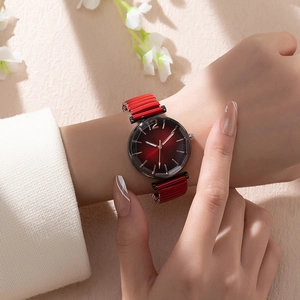Close-up of women's red gradient watch with gold indices and elastic metal strap