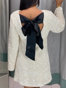 Abito corto bianco con paillettes, maniche lunghe e grande fiocco nero sulla schiena