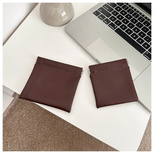 Detail of dark brown leather mini pouches with metal spring closure on a desk